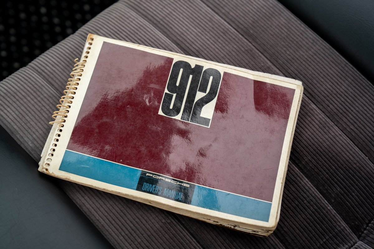 Vintage Porsche 912 driver's manual sits on corduroy seat.