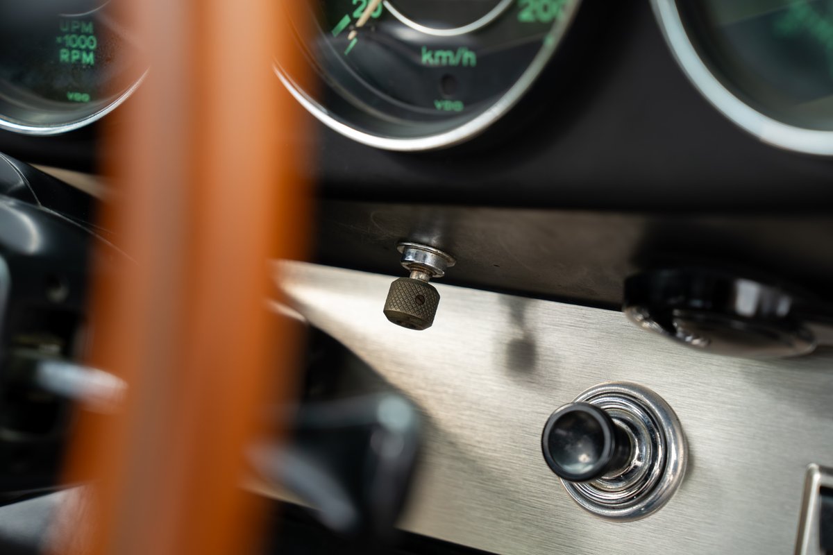 Classic 1965 blue Porsche 912 dashboard with vintage toggle switches and brushed aluminum trim.