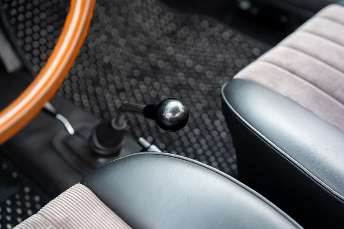Interior of a 1965 blue Porsche 912, showing the wooden steering wheel, shifter, and corduroy seats.