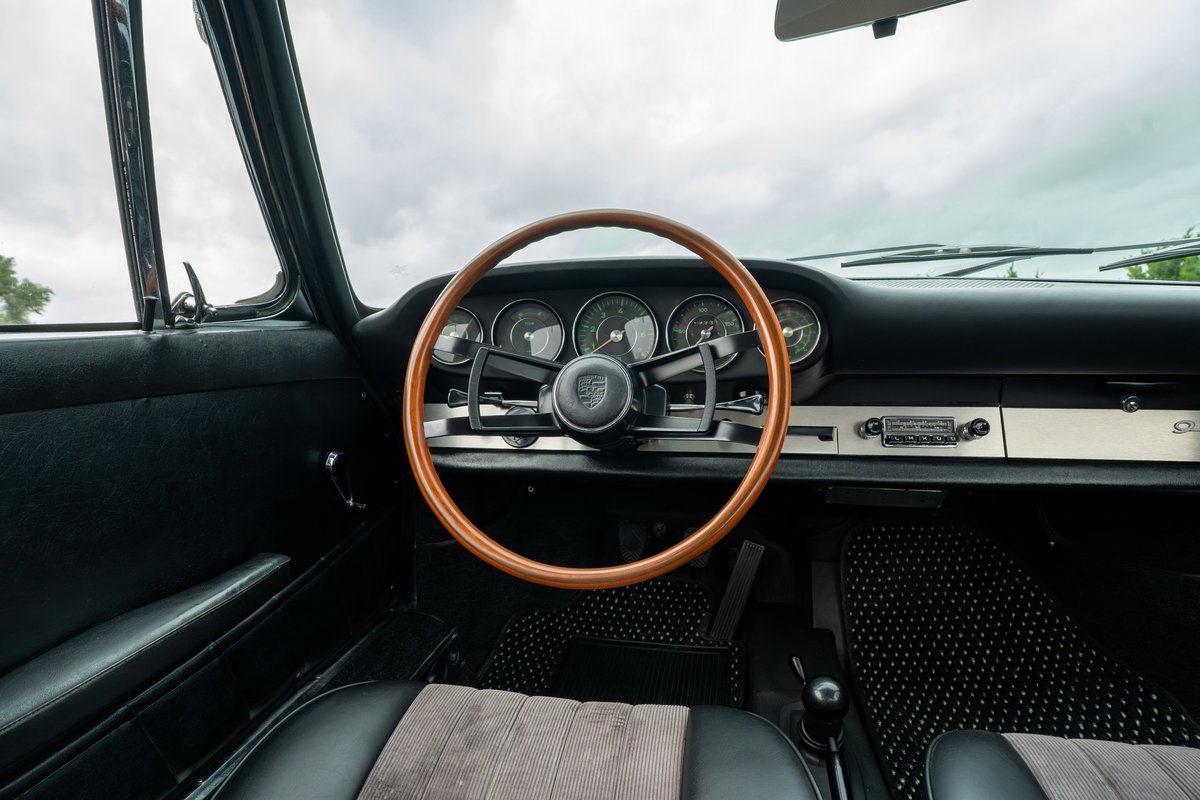 Vintage blue Porsche 912 interior with wood-rimmed steering wheel, classic gauges, and AM/FM radio.