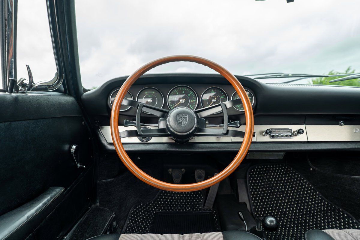 1965 blue Porsche 912 interior with a wood-rimmed steering wheel and classic gauges.