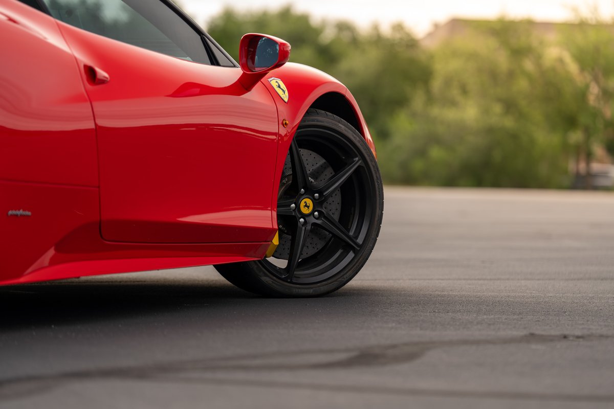 Red Ferrari 458 Italia, side profile, black five-spoke rims, yellow brake calipers.