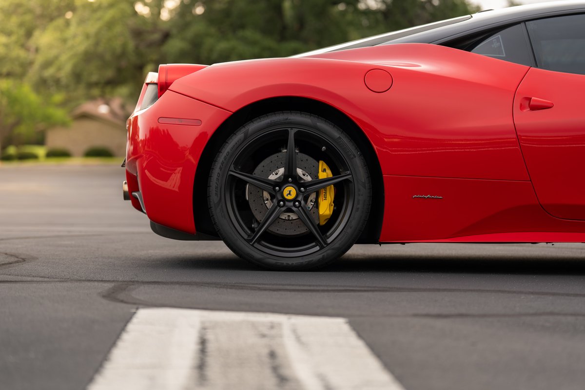 Red Ferrari 458 Italia rear wheel with black 5-spoke rims and yellow brake calipers.