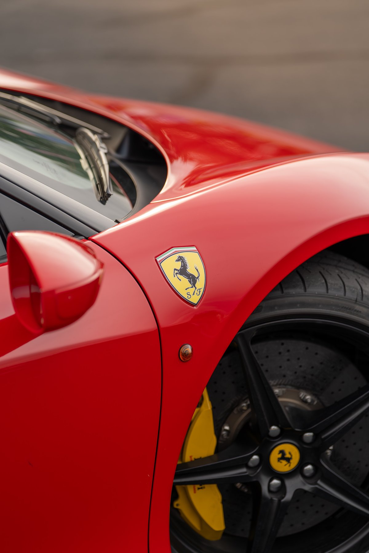 Red Ferrari 458 Italia fender with yellow brake calipers, black rims, and Prancing Horse badge.