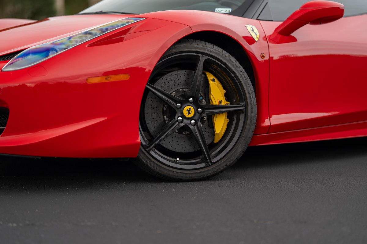Red Ferrari 458 Italia front quarter, showing black five-spoke rims and yellow brake calipers.