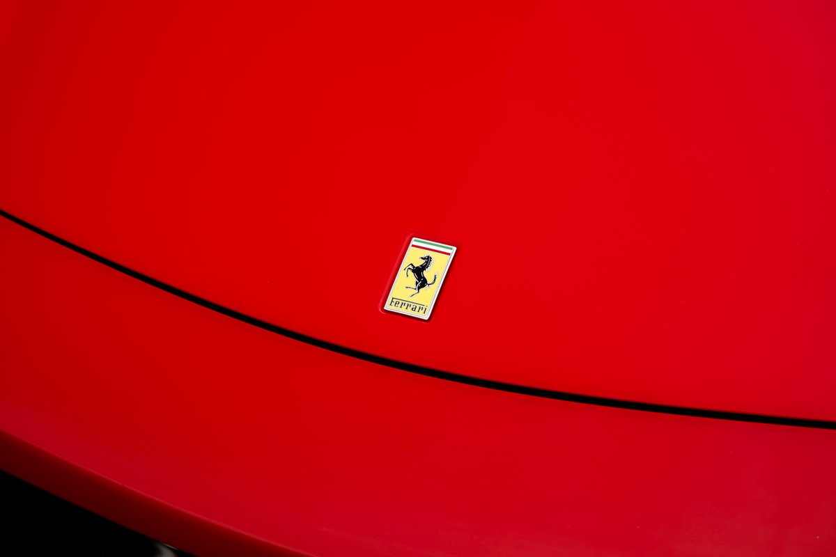 Close-up of the Ferrari Prancing Horse badge on the hood of a red Ferrari 458 Italia.