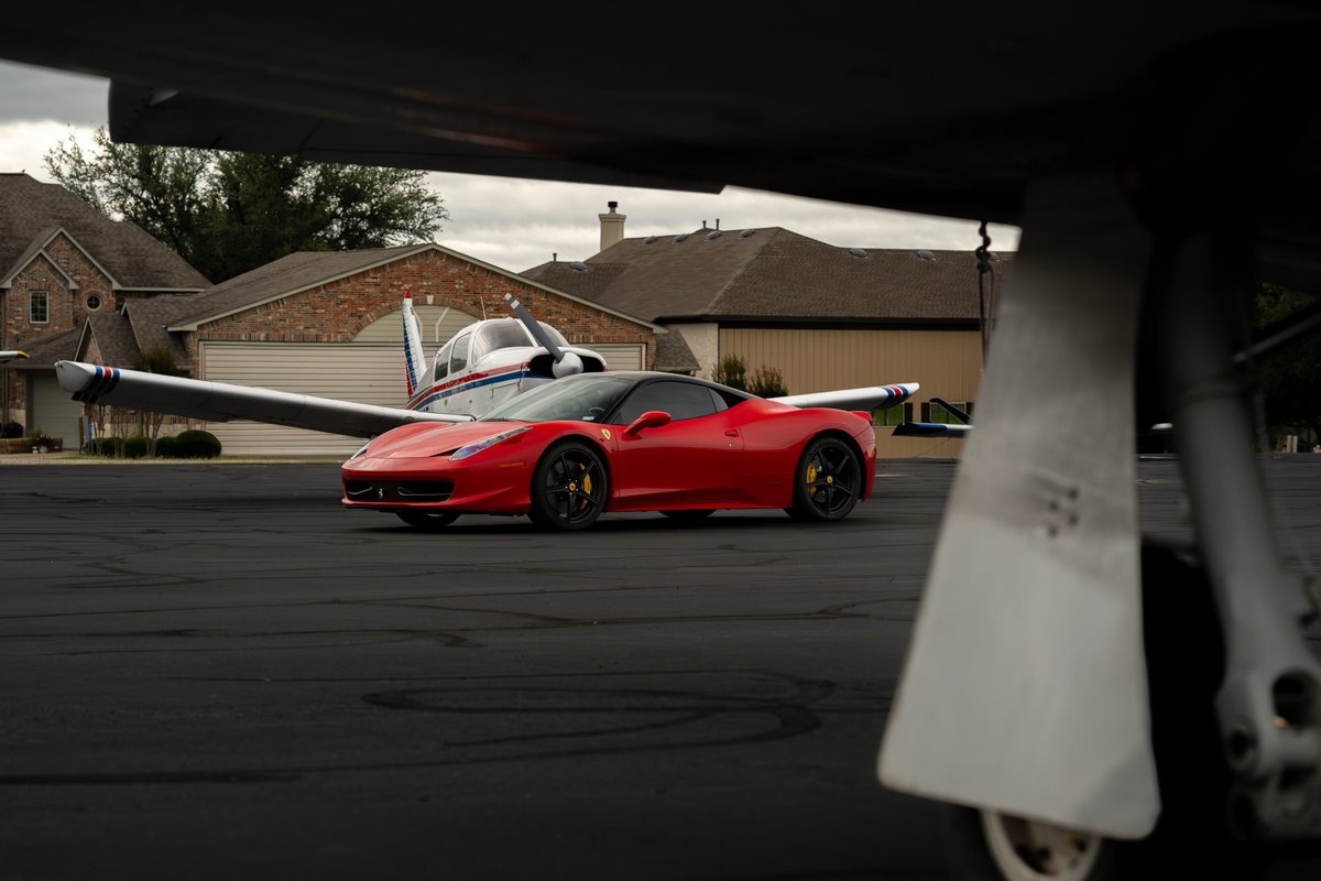 Red Ferrari 458 Italia with black rims and yellow brake calipers on tarmac.