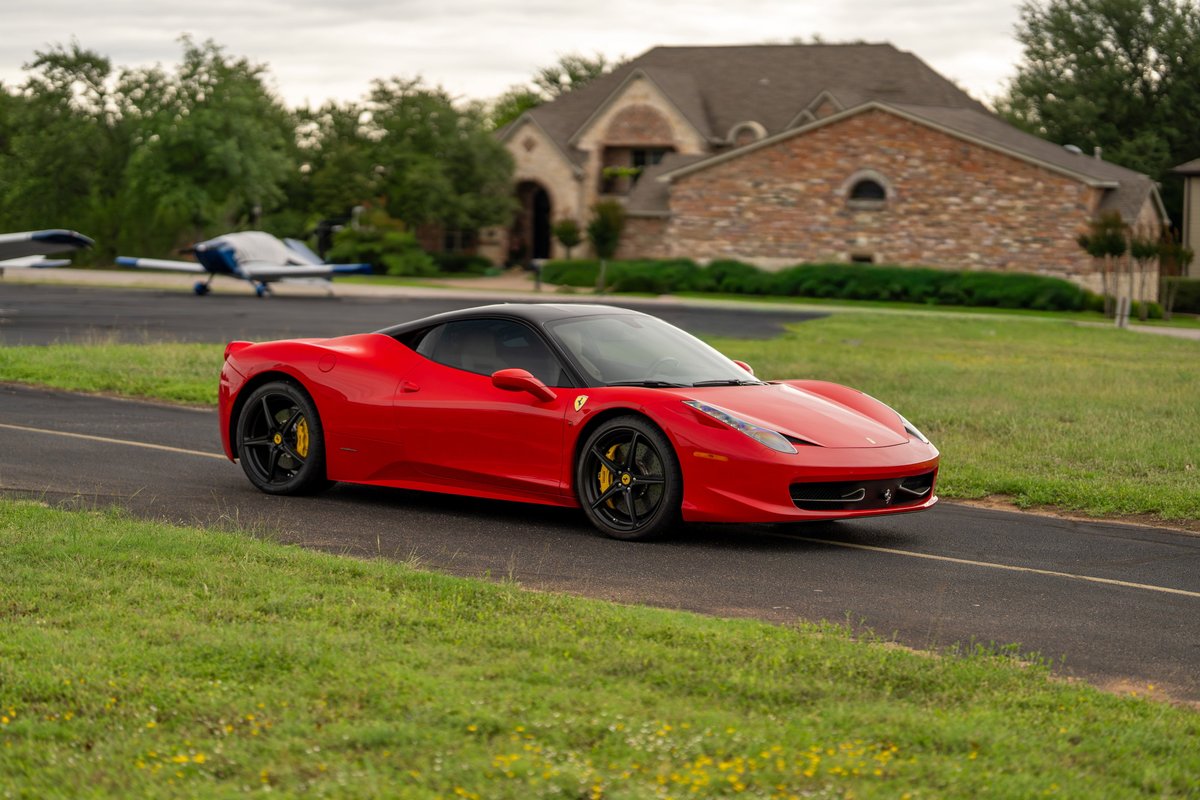 Red Ferrari 458 Italia with black rims and yellow brake calipers on asphalt.