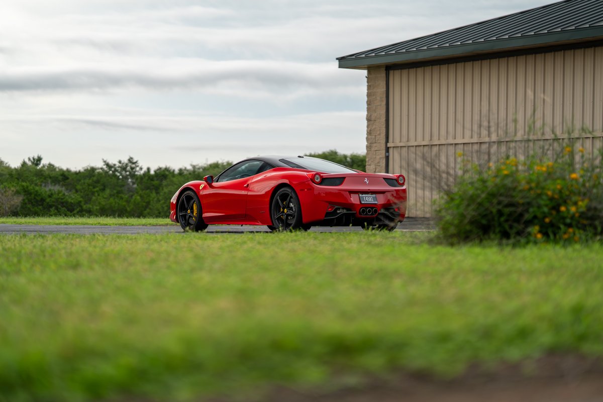 Rear view of a red Ferrari 458 Italia with black rims and yellow brake calipers.