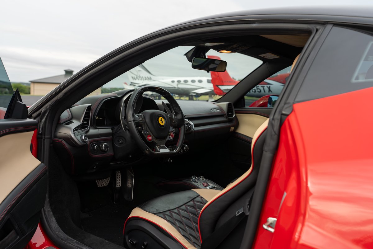 Red Ferrari 458 Italia interior with black and tan diamond-stitched seats and carbon fiber trim.