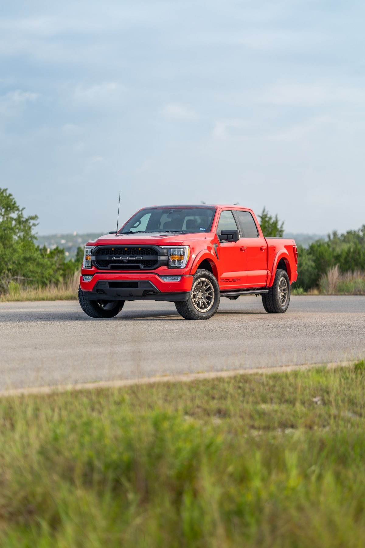 Red 2022 Ford F-150 Roush with black trim and bronze rims driving on asphalt.