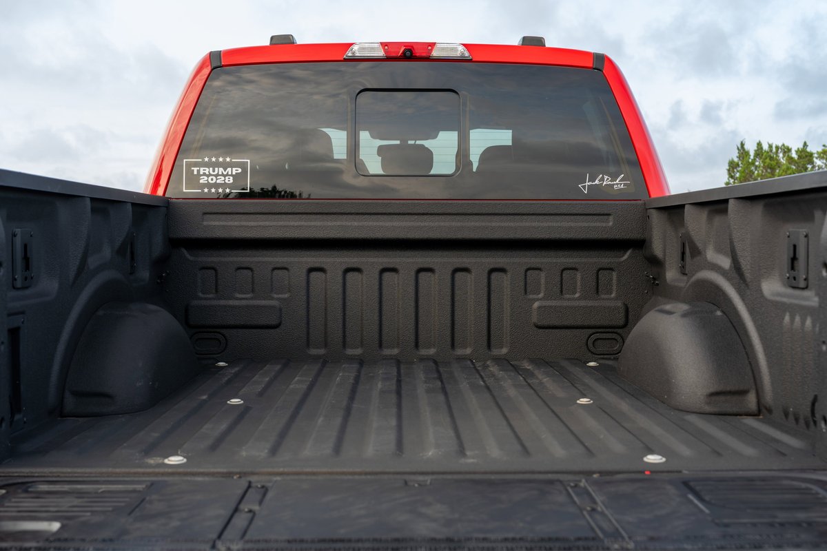 Red Ford F-150 Roush bed with "TRUMP 2020" decal on rear window.