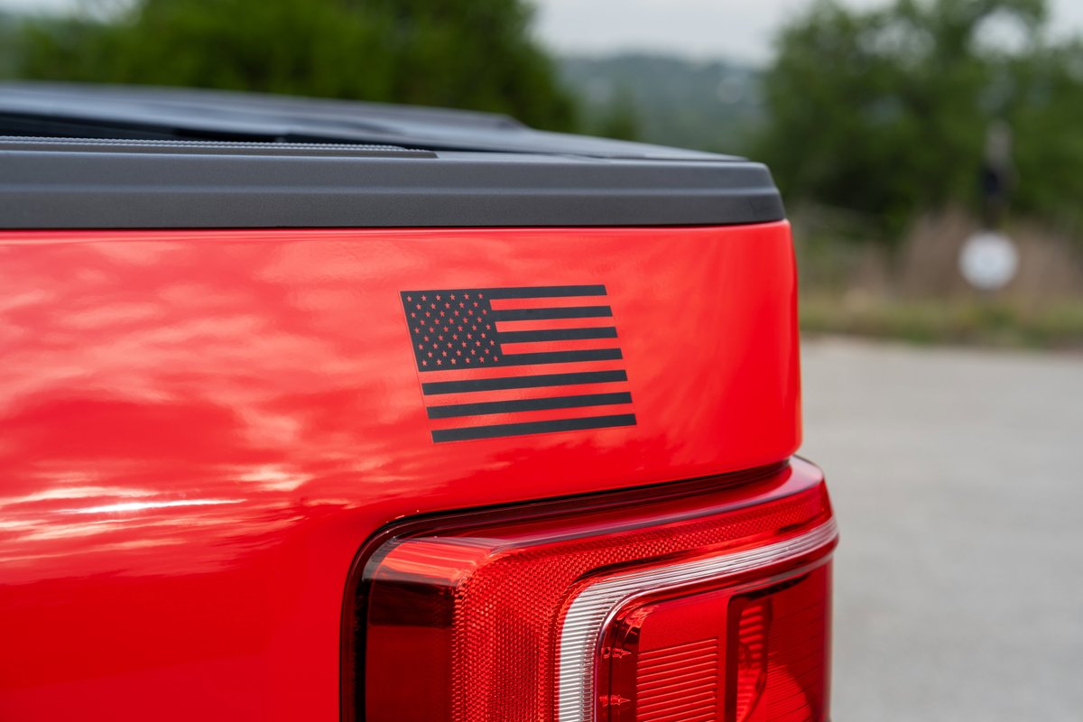Red Ford F-150 Roush with black American flag livery on the rear quarter panel.