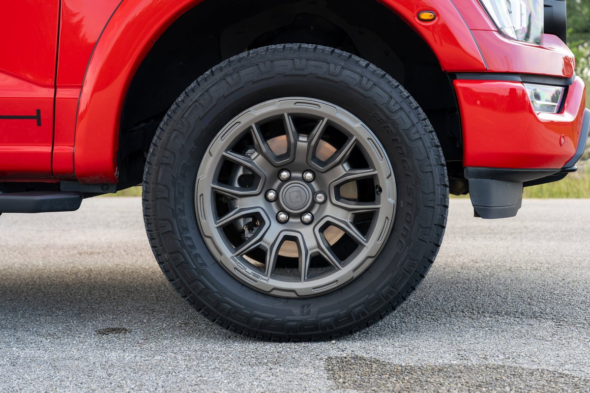 Red 2022 Ford F-150 Roush with gunmetal gray, multi-spoke rims and aggressive all-terrain tires.