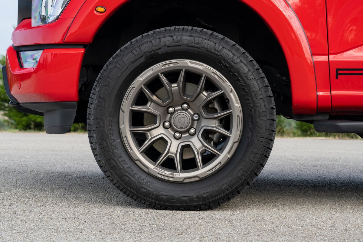 2022 red Ford F-150 Roush tire and alloy rims with dark trim.