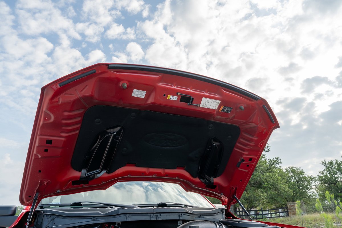 Open hood of a red 2022 Ford F-150 Roush showing insulation and bracing.