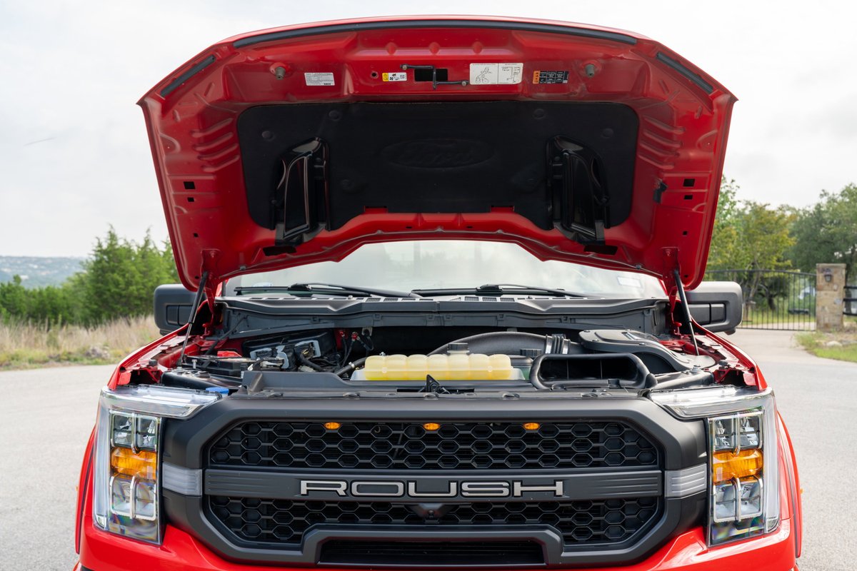 2022 red Ford F-150 ROUSH with hood open showing engine bay and ROUSH grille.