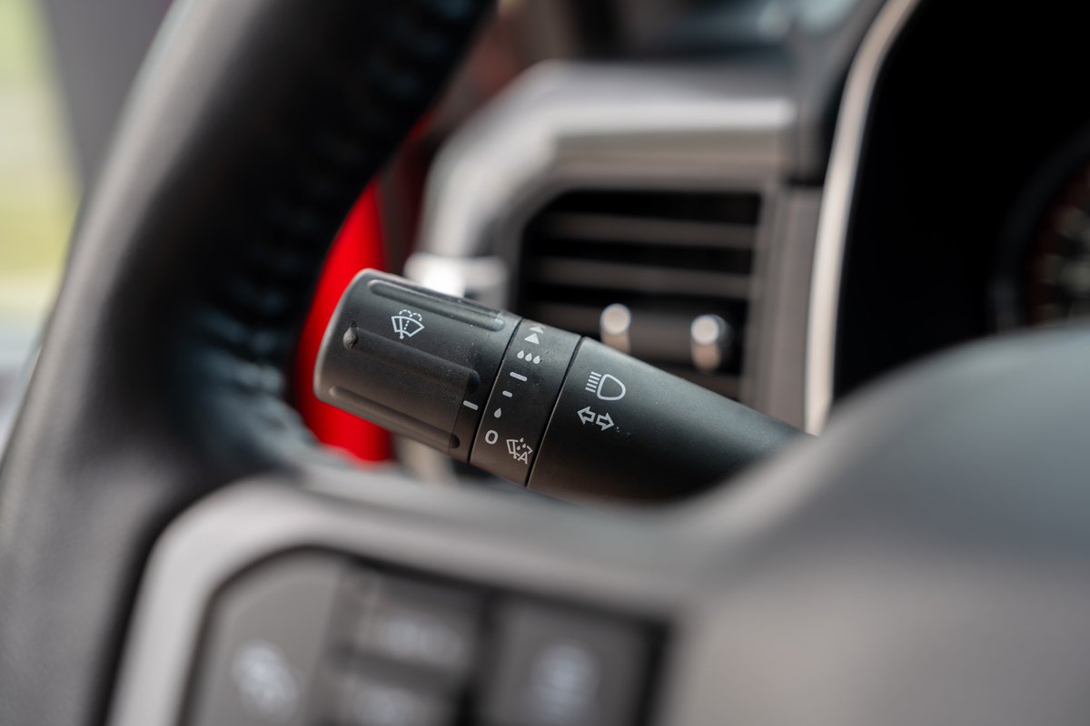 Close-up of a red 2022 Ford F-150 Roush steering wheel with wiper and light controls.