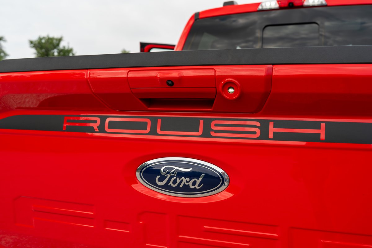 Red Ford F-150 Roush tailgate with black trim and chrome Ford oval badge.