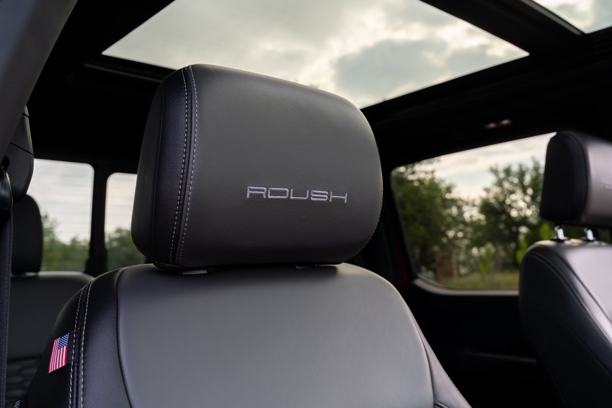 Interior shot of a 2022 red Ford F-150 Roush showing the embossed "ROUSH" logo on the headrest.
