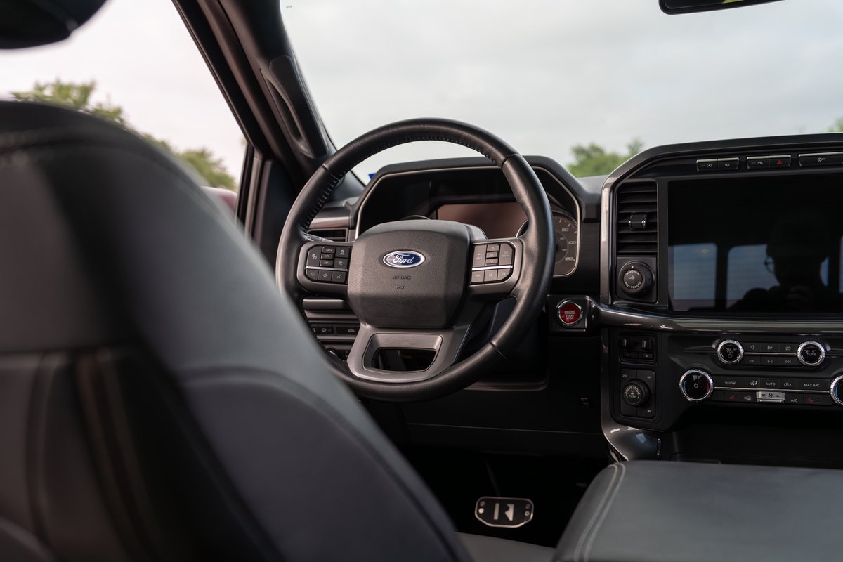 Interior view of a red 2022 Ford F-150 Roush pickup truck, showing the steering wheel and center console.