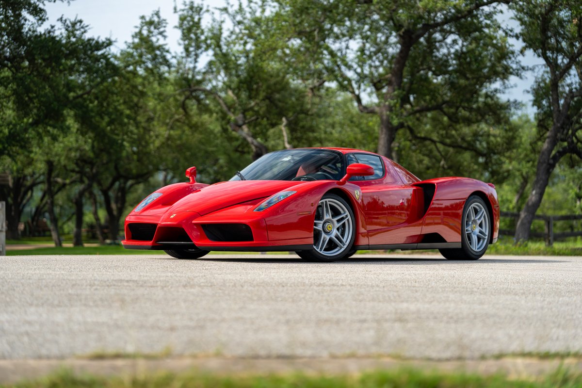Red 2003 Ferrari Enzo with five-spoke alloy rims, parked outdoors on asphalt.
