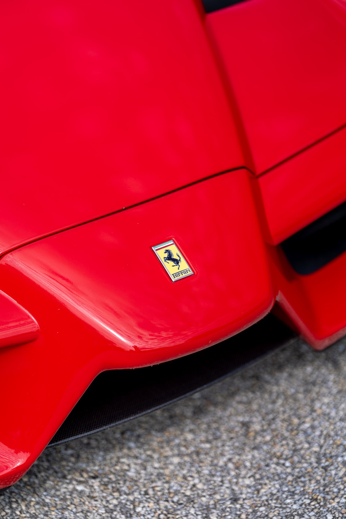 Close-up of the Ferrari Prancing Horse emblem on the Rosso Corsa hood of a 2003 Ferrari Enzo.
