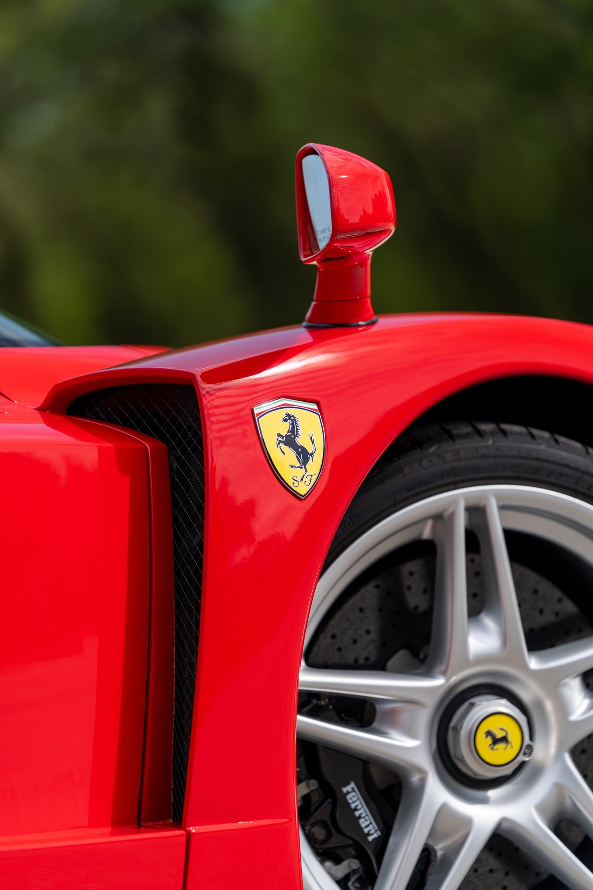 Red Ferrari Enzo with Scuderia shields, iconic mirrors, and five-spoke alloy rims.