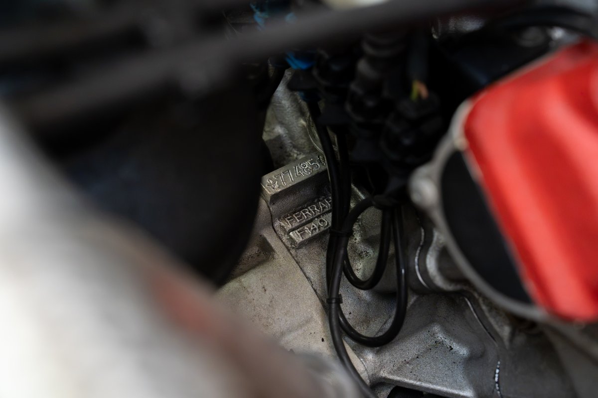 Close-up of the "FERRARI F140" engine block stamping in a Rosso Corsa Enzo.