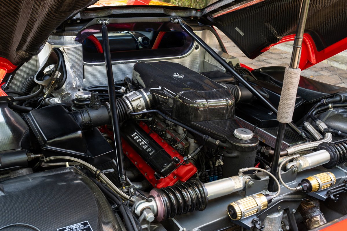 Ferrari Enzo engine bay: Rosso Corsa V12, carbon fiber intake, coilover suspension.