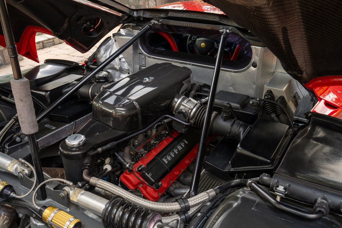 2003 Ferrari Enzo engine bay in Rosso Corsa. Carbon fiber intake and red Ferrari engine covers.