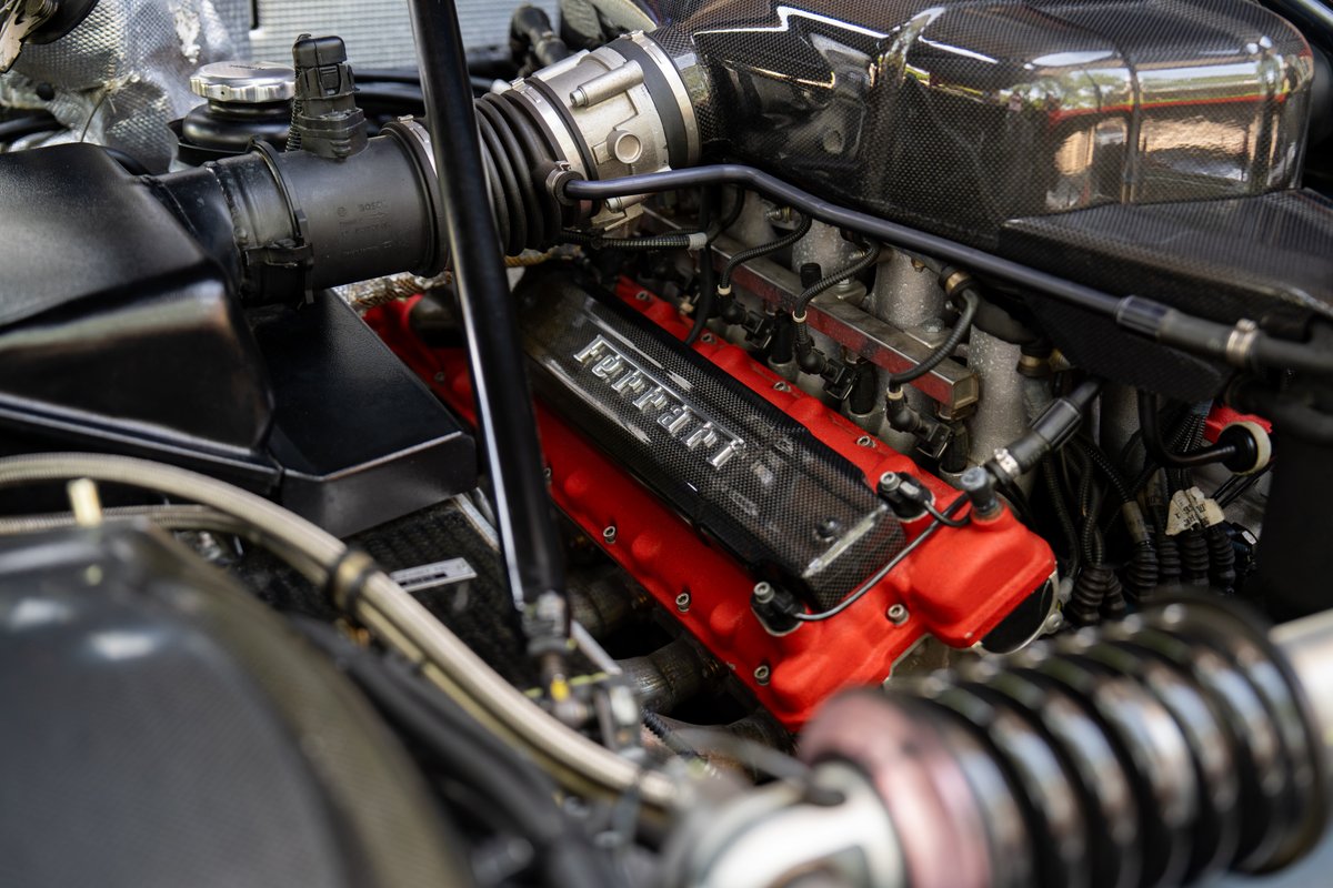 Ferrari Enzo engine bay with red valve covers and carbon fiber trim.