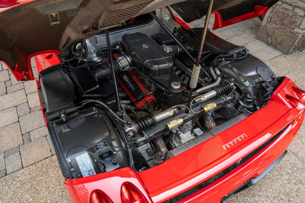 Rosso Corsa 2003 Ferrari Enzo engine bay with exposed carbon fiber and Ferrari branding.