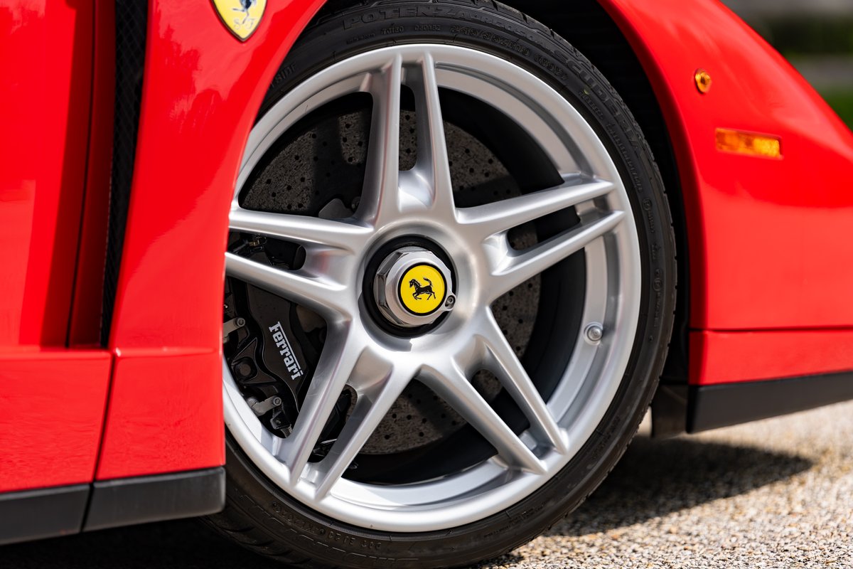 Close-up of a red Ferrari Enzo wheel with silver five-spoke rims and Ferrari brake calipers.