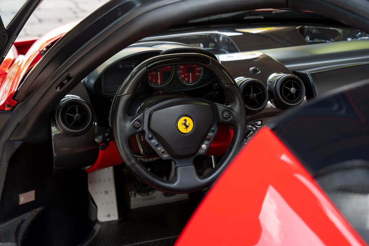 Rosso Corsa 2003 Ferrari Enzo interior with carbon fiber trim and iconic steering wheel.