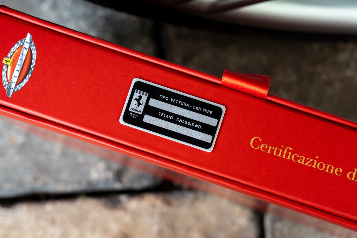 Close-up of red Ferrari Enzo's Classiche certification plate and chassis number.