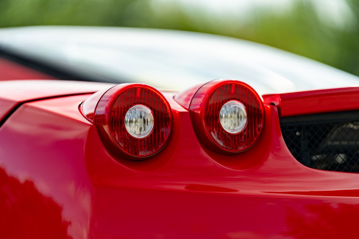 Rear view of a red 2003 Ferrari Enzo with circular taillights and mesh grille detail.