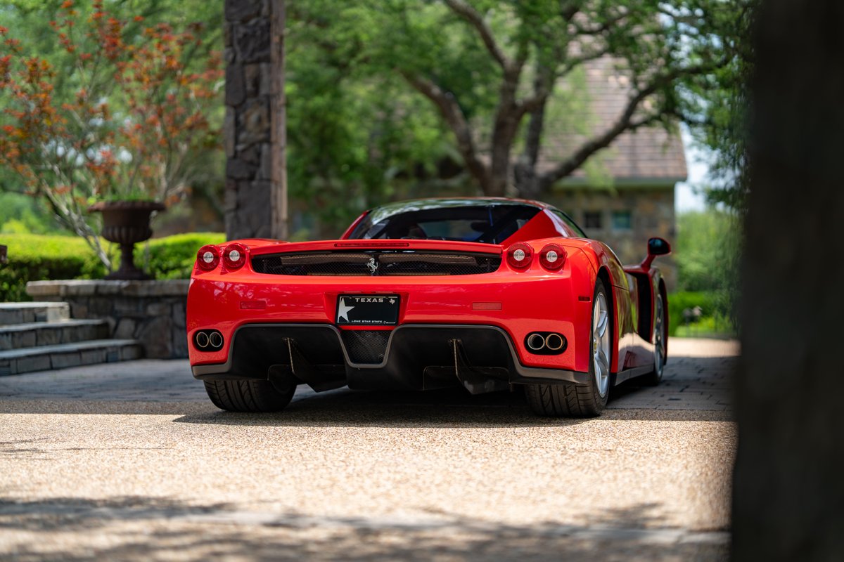 Rosso Corsa 2003 Ferrari Enzo rear view with quad exhaust, twin taillights, and alloy rims.