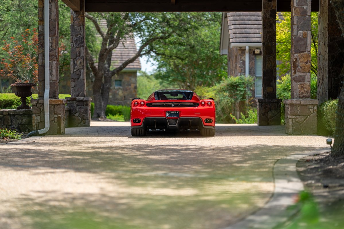 Rear view of a red 2003 Ferrari Enzo with black trim and dark rims.