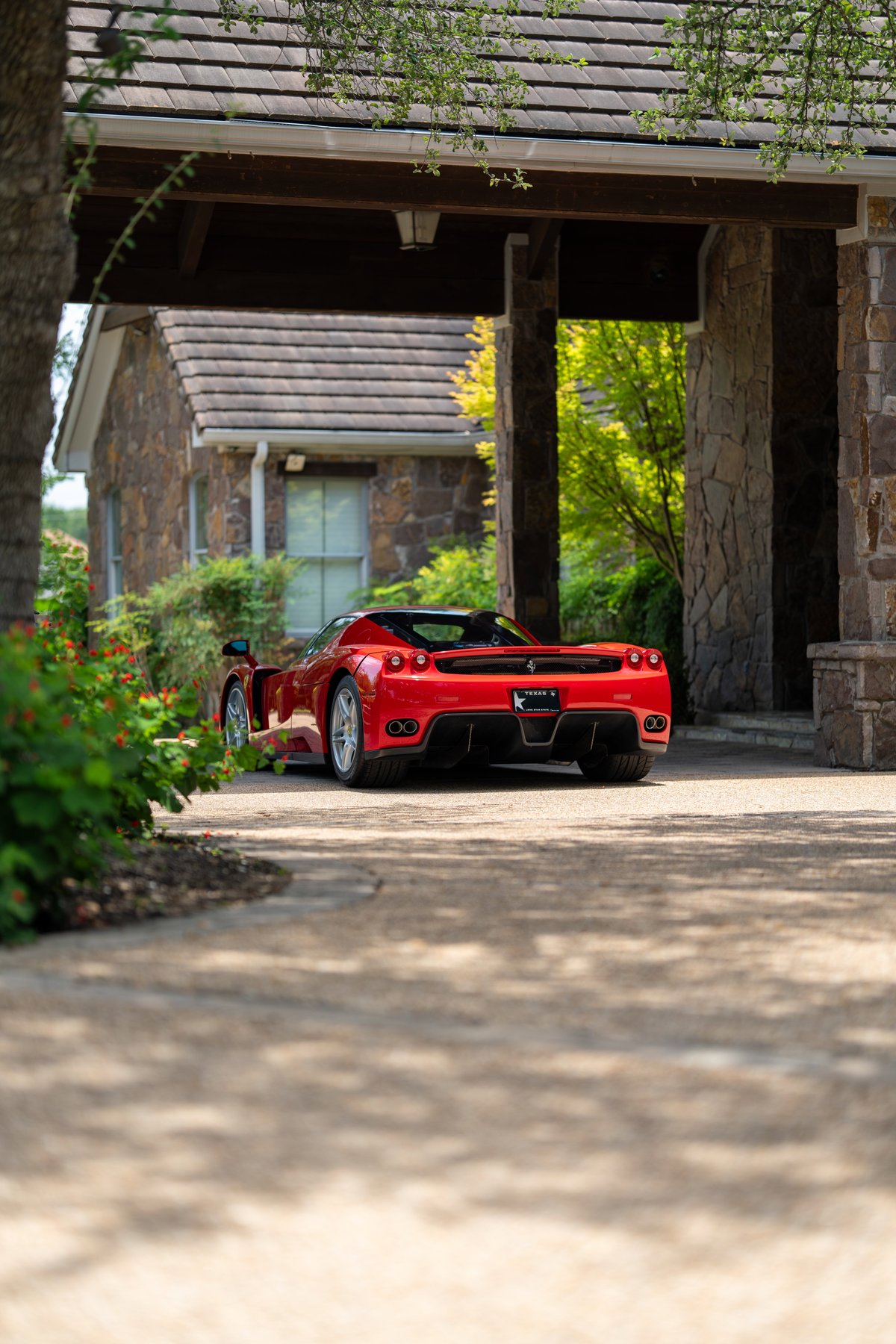 Rosso Corsa 2003 Ferrari Enzo with silver rims and black trim seen from rear.