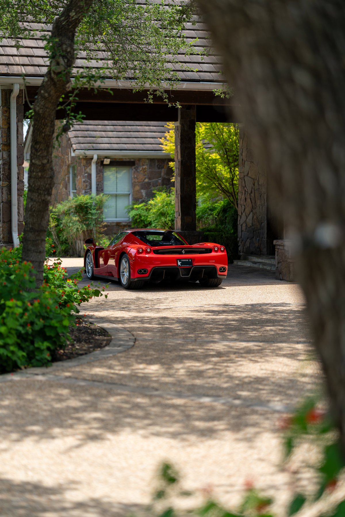 Red 2003 Ferrari Enzo parked in driveway, with multi-spoke rims.