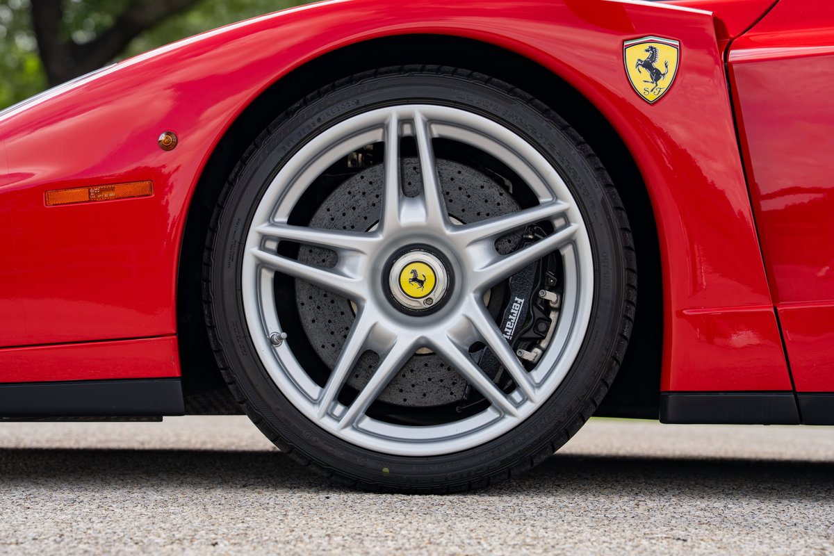 Close-up of a red Ferrari Enzo wheel and brake caliper with Ferrari logo.