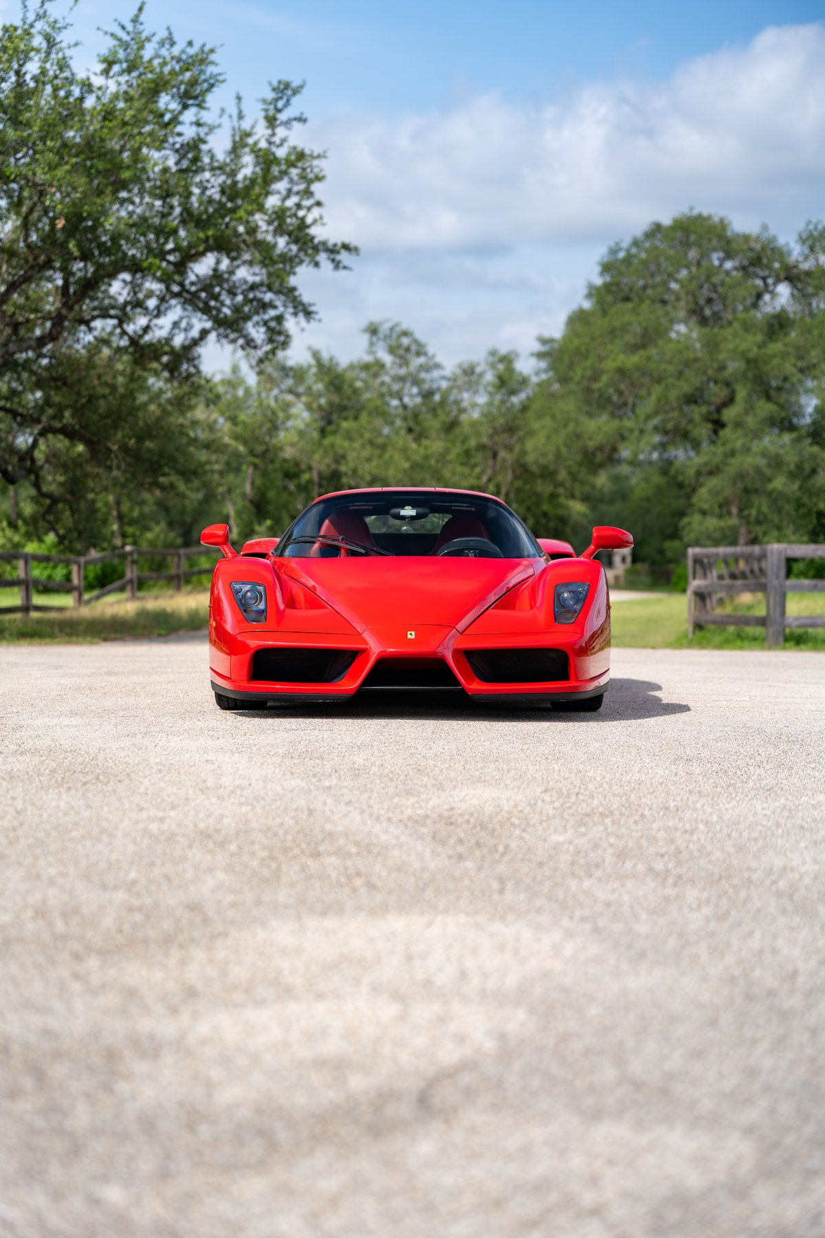 Front view of a Rosso Corsa 2003 Ferrari Enzo supercar with black trim and black wheels parked outdoors.