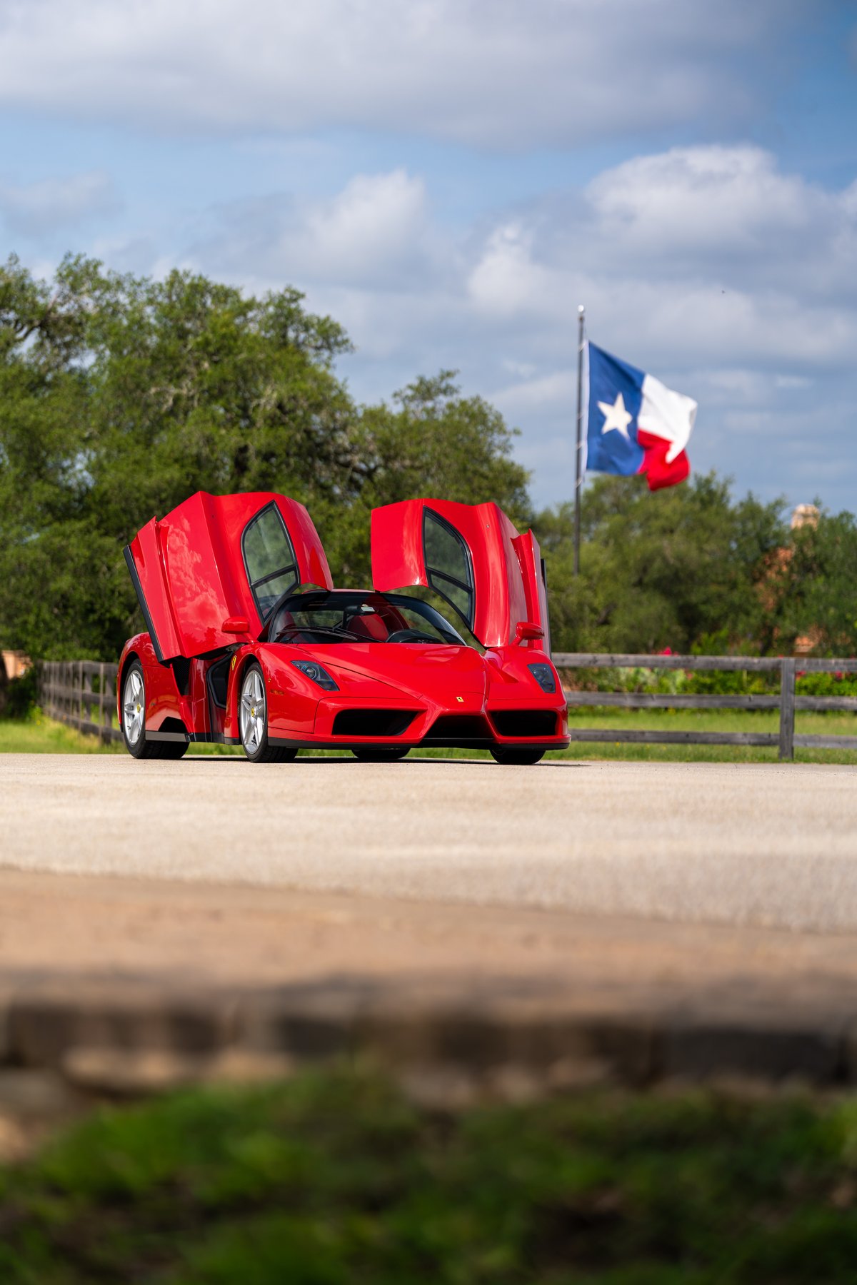 Rosso Corsa 2003 Ferrari Enzo with butterfly doors open, Texas flag in background.