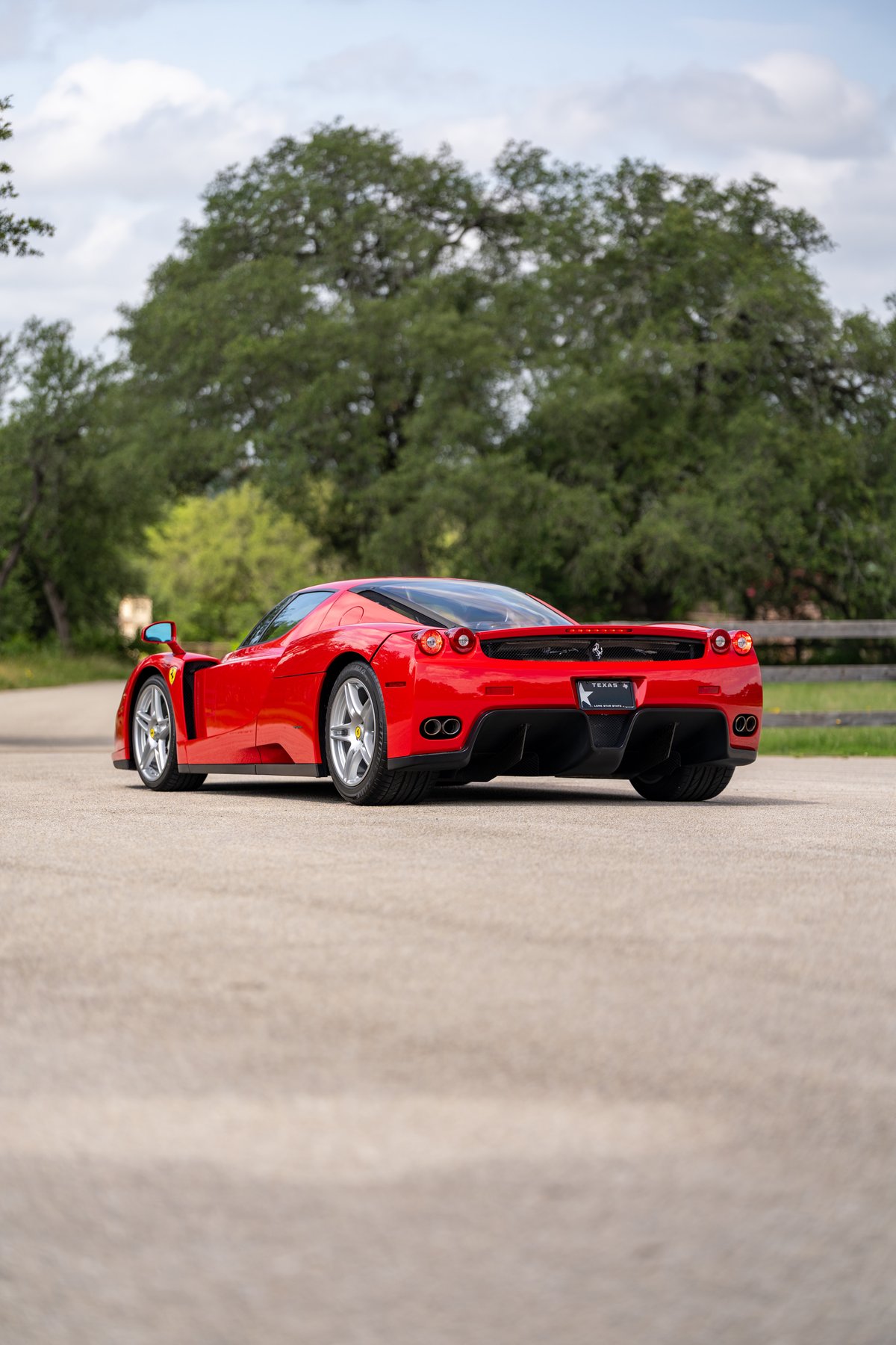 Rear view of a Rosso Corsa 2003 Ferrari Enzo with silver rims and black trim.