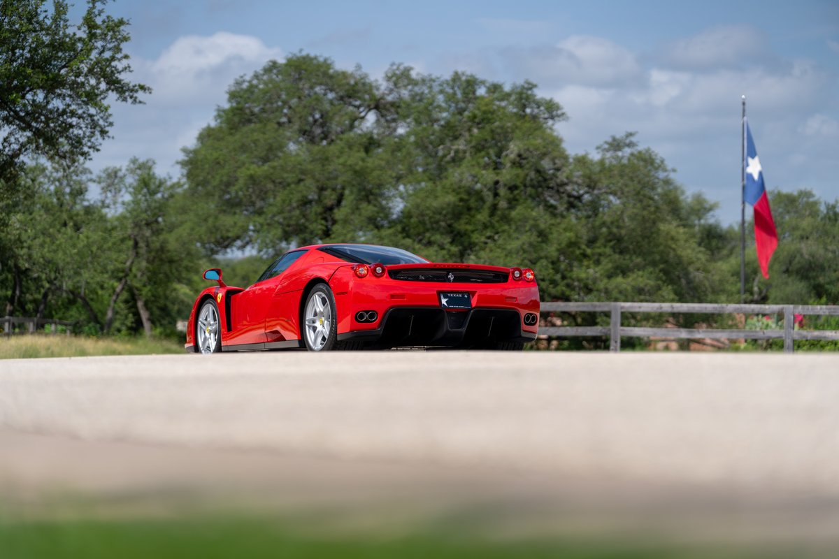 Red 2003 Ferrari Enzo with silver rims and black trim, Texas flag in background.