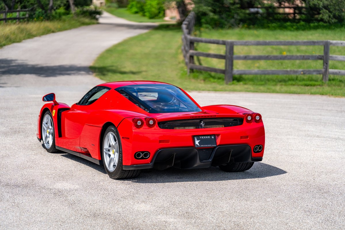 Rear 3/4 view of a Rosso Corsa Ferrari Enzo with silver multi-spoke rims.