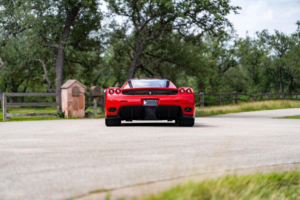 Rear view of a red 2003 Ferrari Enzo with quad exhaust pipes and black diffusers.