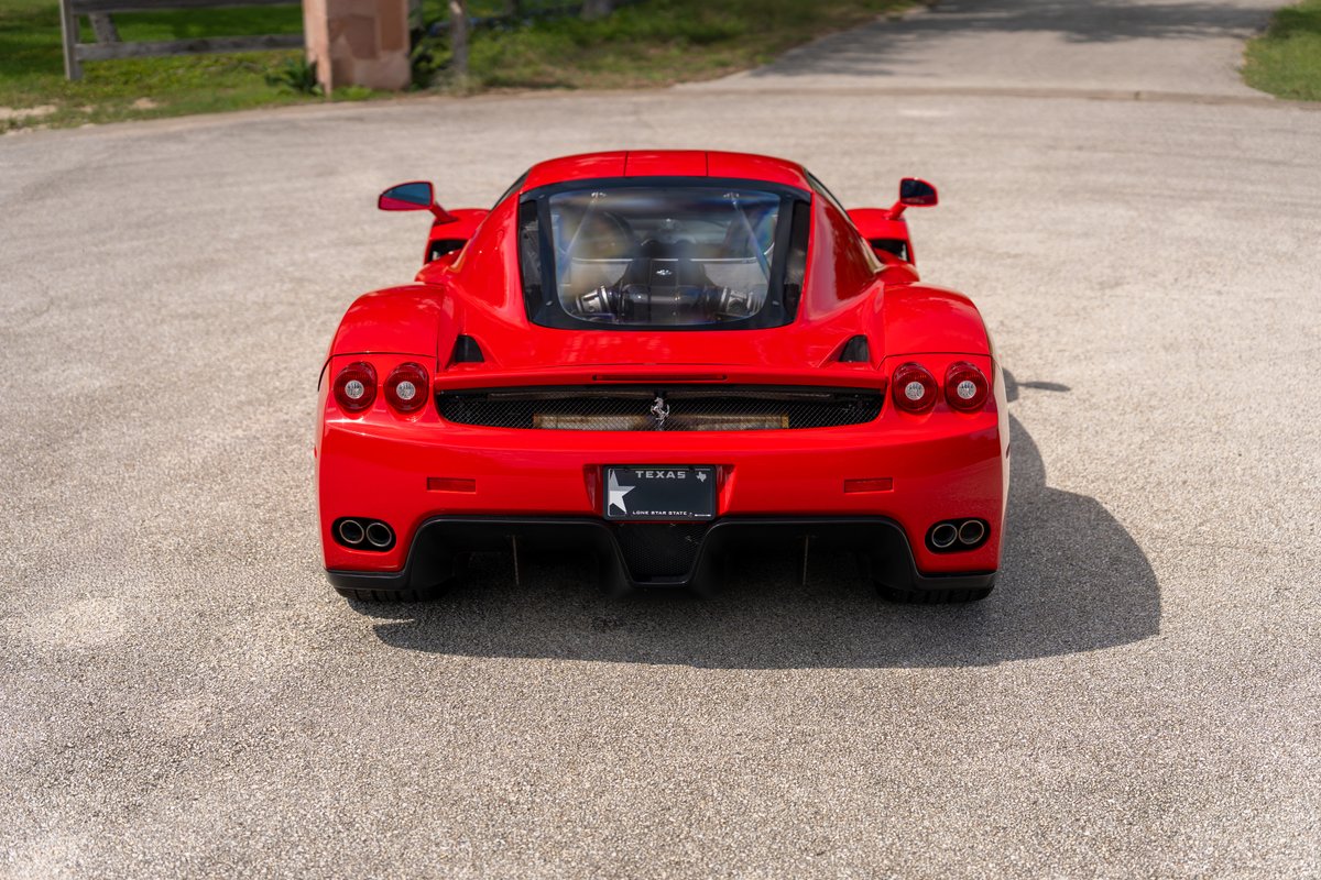 Rosso Corsa 2003 Ferrari Enzo, rear view, showcasing quad exhaust tips and wide body trim.
