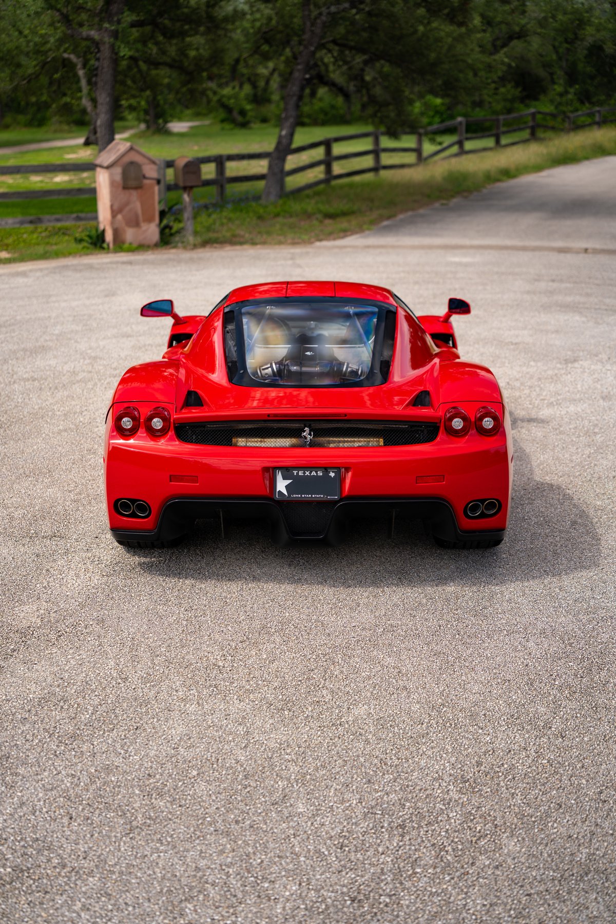 Rear view of a red 2003 Ferrari Enzo with a Texas license plate.